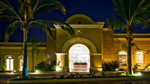 A hotel entrance with a large archway, palm trees, and well-lit surroundings.