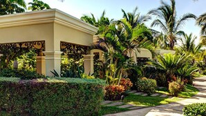 A well-maintained garden with palm trees, a pathway, and a building with decorative ironwork.