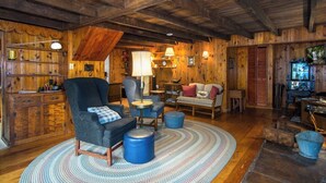 Ein rustikales Interieur mit Holzwänden, einer Couch, Sesseln und einem Essbereich.