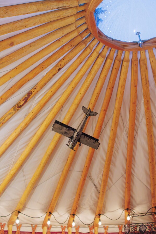 Una yurta con estructura de madera y una abertura circular en la parte superior.