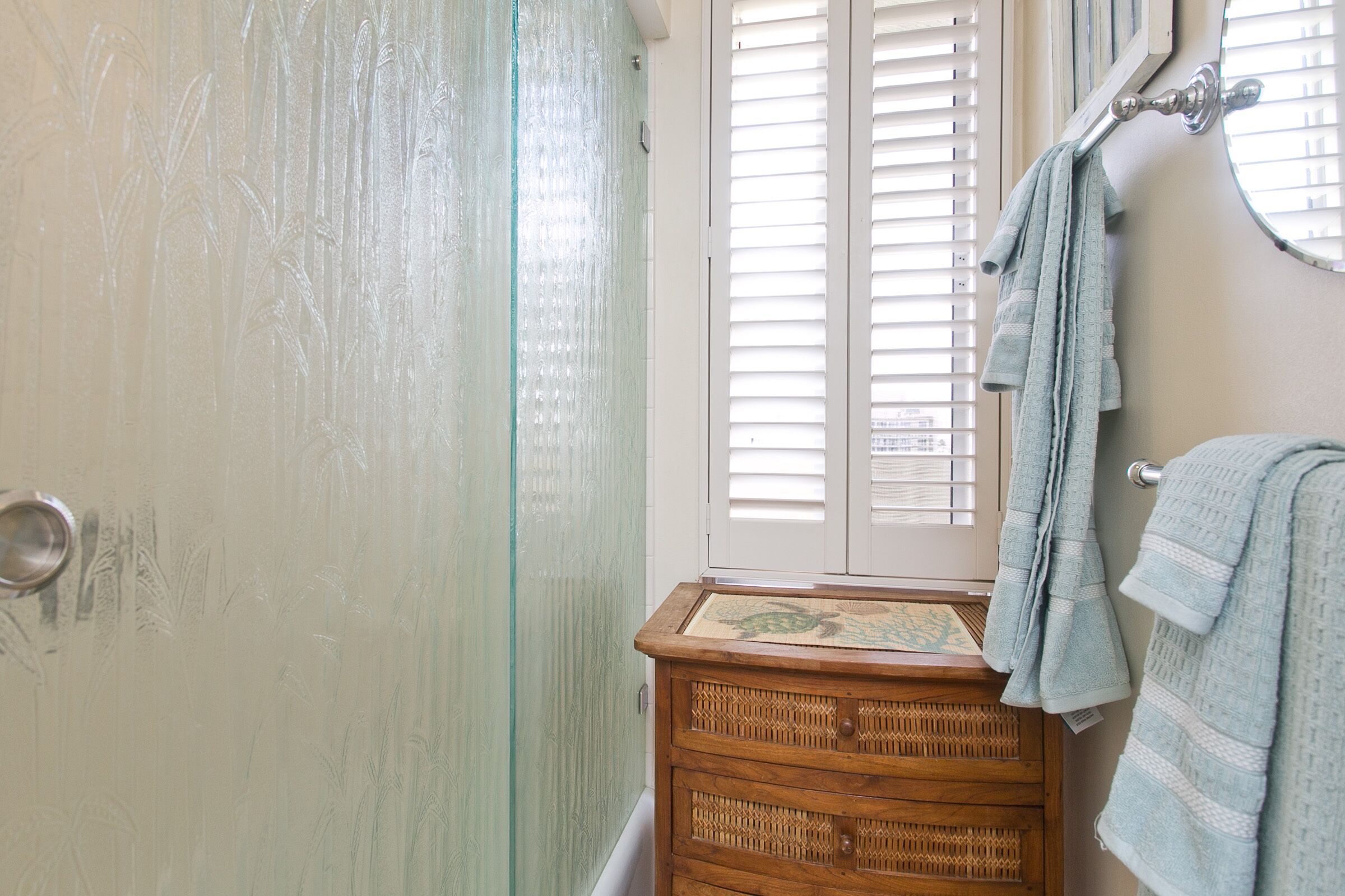A bathroom with a wooden vanity, a towel rack, and a window with blinds.
