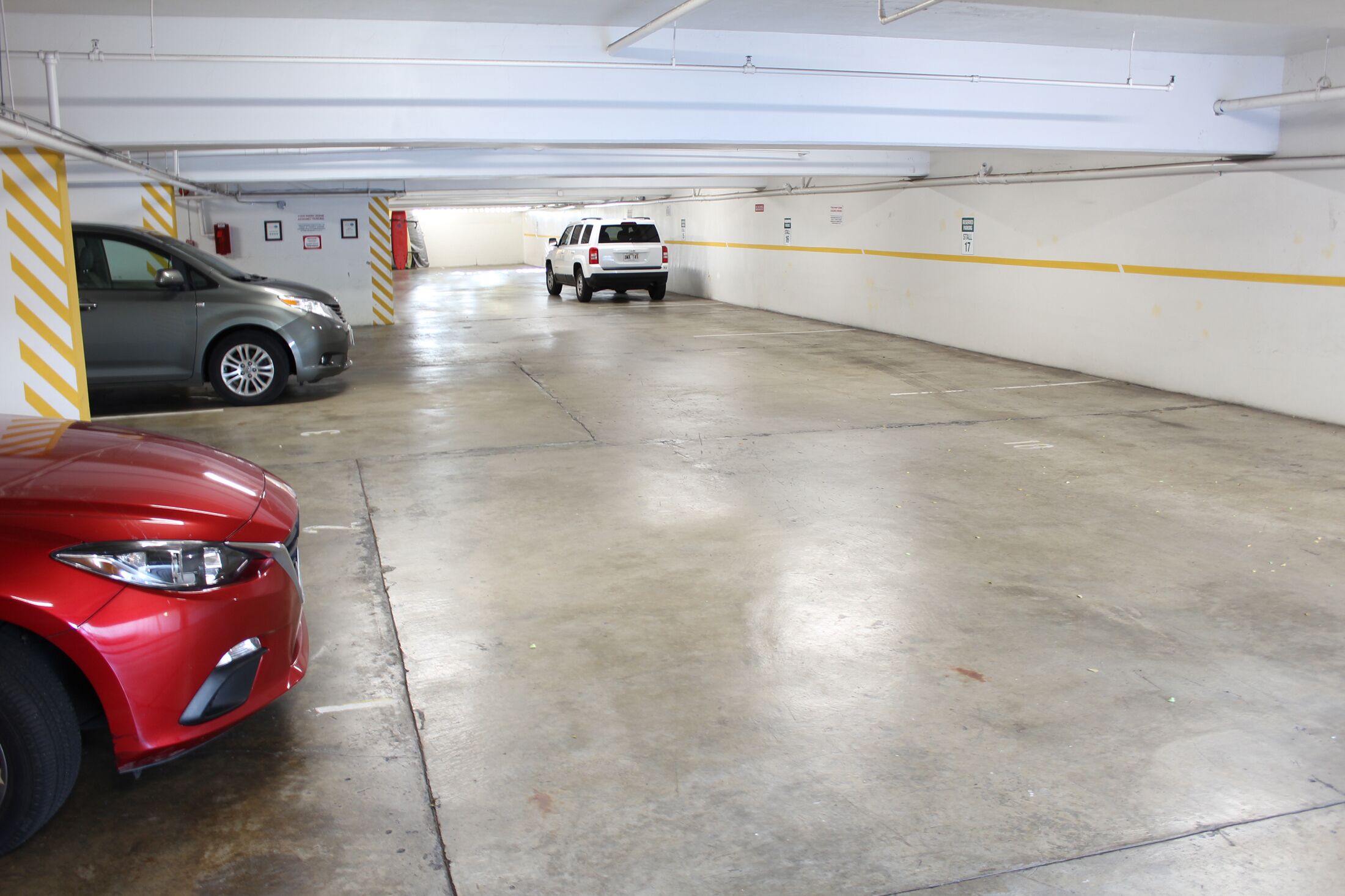 A parking garage with three cars parked.