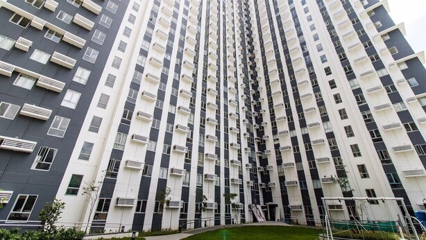 A high-rise residential building with a modern design, featuring multiple balconies and air conditioning units.