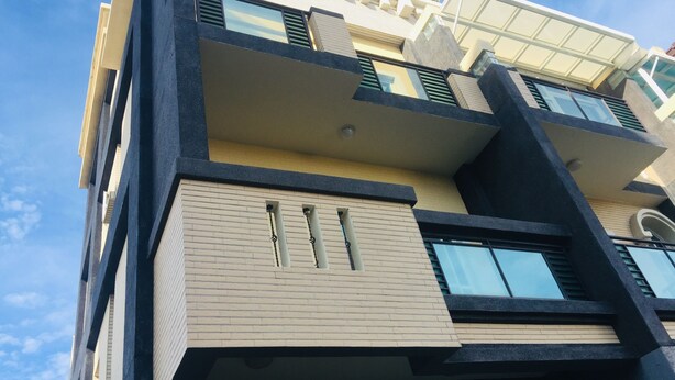 A multi-story building with a modern architectural design, featuring balconies, large windows, and a mix of beige and dark-colored exterior walls. - Coffee Bear (Hengchun)