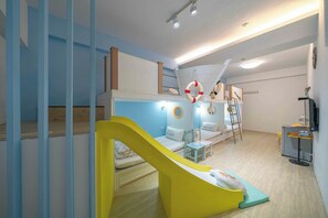 A children's play area with a slide, a sofa, and a small table. - Sigang Grandma House (Tainan)