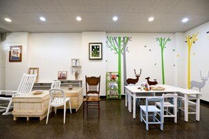 Una sala de juegos para niños con una mesa blanca, sillas y una estantería.