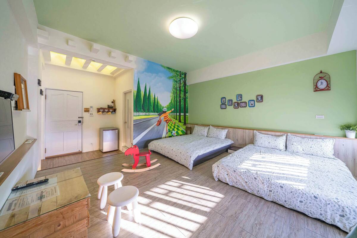 Quarto com cama, um balanço de cavalo, escrivaninha com cadeira e parede com quadros.