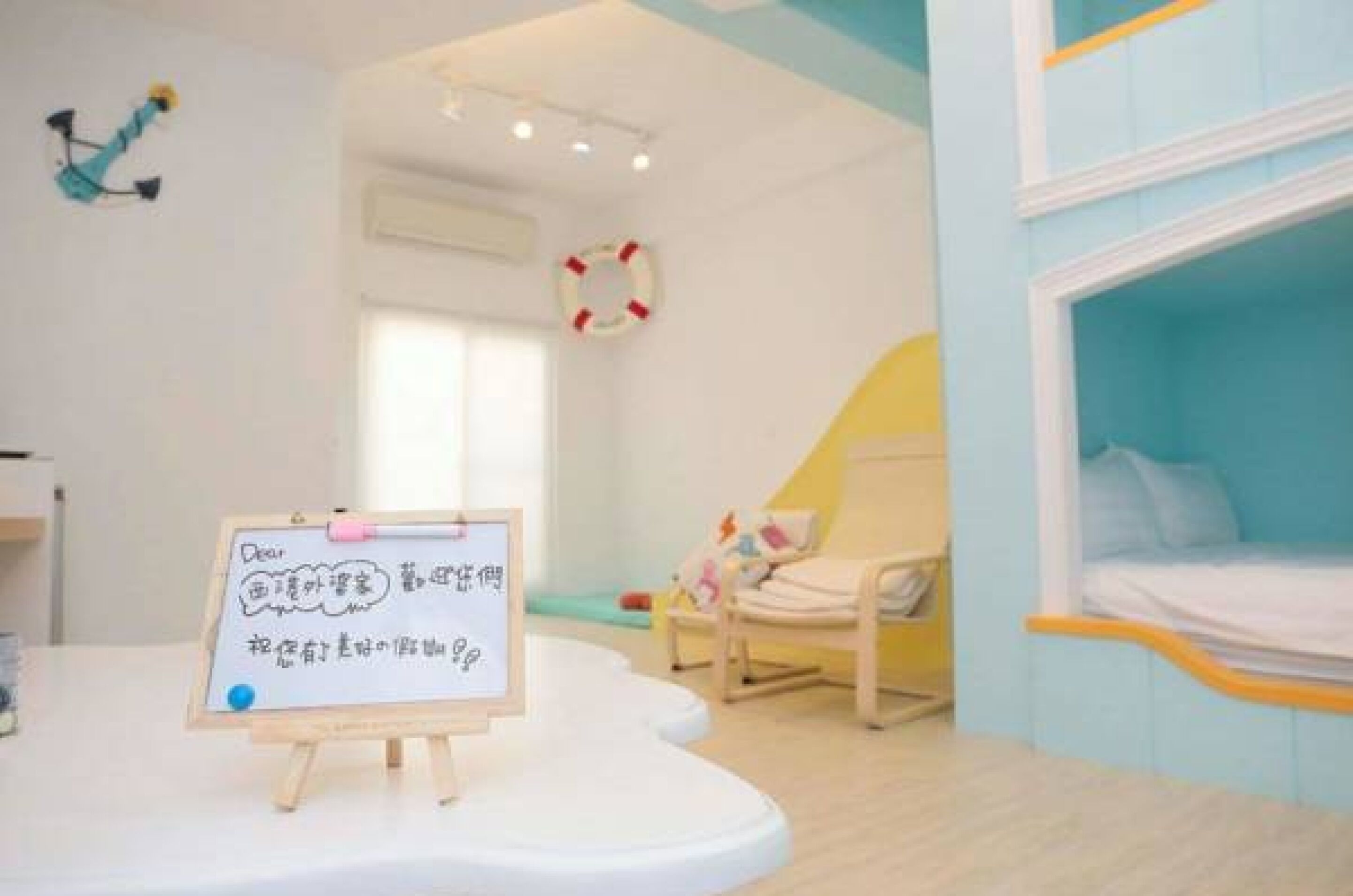 A child-friendly room with a bed, a small chair, and a whiteboard with writing.