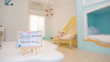 A child-friendly room with a bed, a small chair, and a whiteboard with writing.