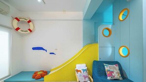 Ein kinderfreundliches Zimmer mit Rutsche, Bett und einer Rettungsboje an der Wand.