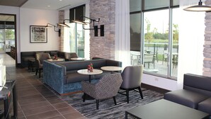 Een moderne lounge met zitplaatsen, tafels en grote ramen met uitzicht op het omliggende landschap.