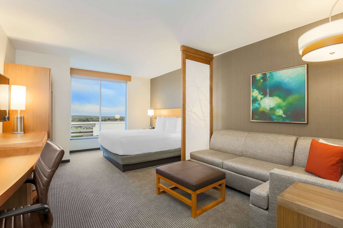 A hotel room with a bed, a sofa, a desk, and a chair.