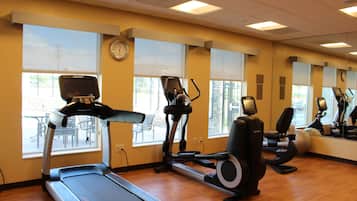 Un gimnasio con cintas de correr, elípticas y bicicletas estáticas.