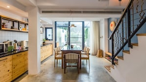 A modern kitchen with wooden cabinets, a dining table with chairs, and a staircase with a unique railing design. - Tree House (Tainan)