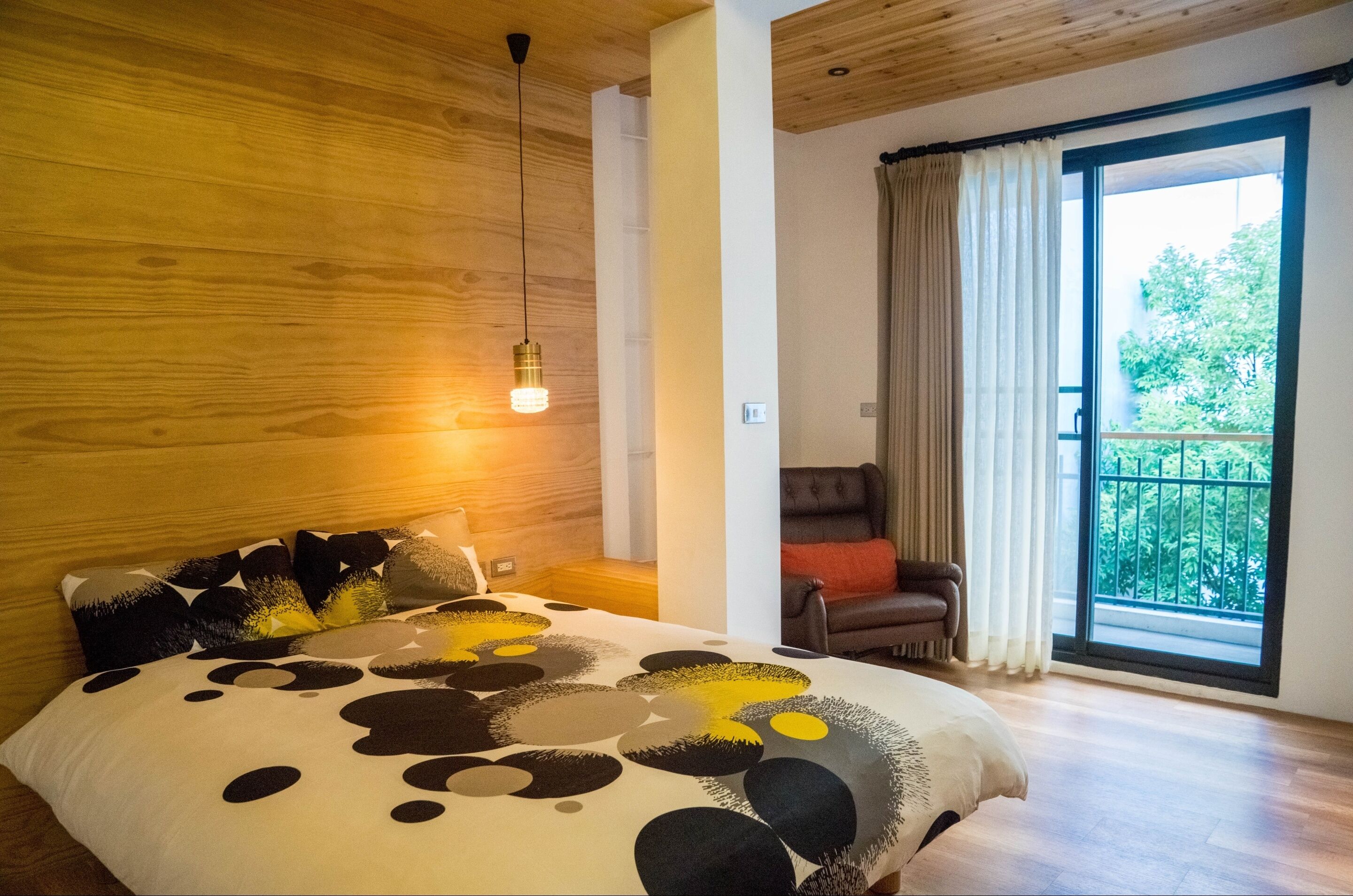 Une chambre à coucher avec un lit, une chaise, une fenêtre et un plafond en bois.