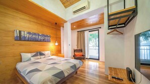 A bedroom with a bed, a chair, a TV, and a wooden shelf with a remote control. - Tree House (Tainan)