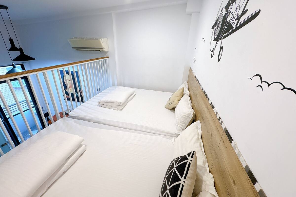 Quarto de hotel com duas camas, cabeceira de madeira, painel na parede e varanda com grades.