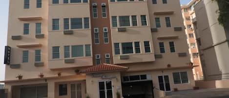 A multi-story hotel with a central entrance, multiple windows, and a flat roof.