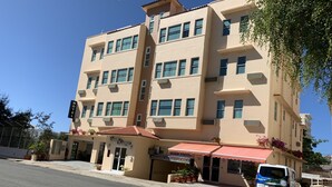 A multi-story hotel with a beige facade, a red awning, and a sign welcoming visitors to Puerto Rico. - Dreams Miramar (San Juan)