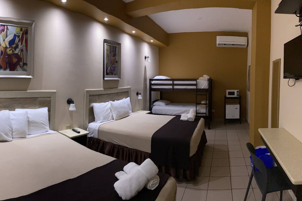 A hotel room with two beds, a shower, a small bedside table, a TV, and a microwave.