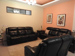 A living room with two black leather sofas, a small side table, and a decorative plant. - Dreams Miramar (San Juan)
