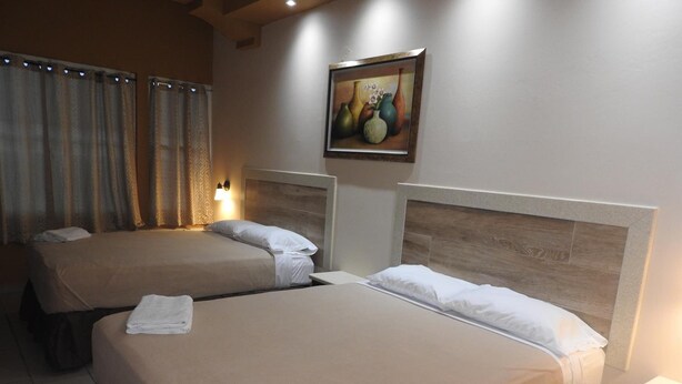 A hotel room with two beds, a painting on the wall, and a window with curtains. - Dreams Miramar (San Juan)
