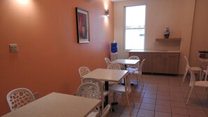 A dining area with white tables and chairs, a framed picture on the wall, and a window with a view. - Dreams Miramar (San Juan)