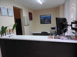 A reception area with a desk, a computer, a chair, and a framed picture on the wall. - Dreams Miramar (San Juan)