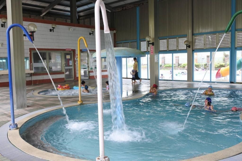 An indoor swimming pool with multiple water features and a tiled floor.