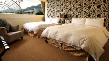 A hotel room with two beds, a sofa, a piano, and a view of a building through a skylight.