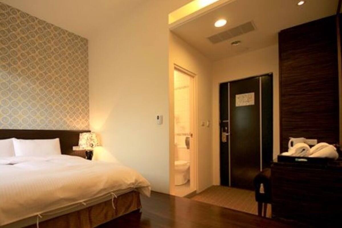 Une chambre d’hôtel comprenant un lit, une table de chevet, un bureau, une chaise, une armoire et une porte donnant accès à la salle de bain.