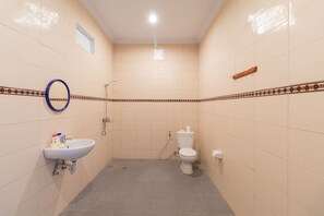 A small bathroom with a sink, toilet, and shower. - Kusuma Guesthouse (Tibubeneng)