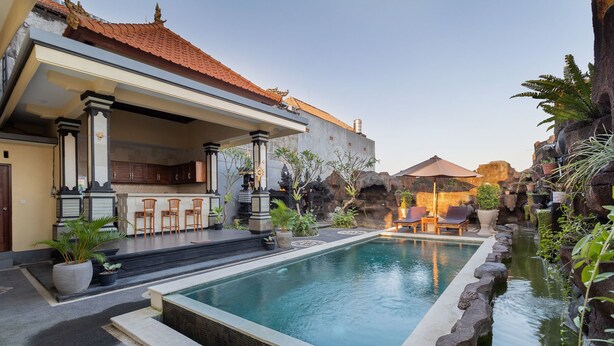 Zona de piscina con bar y asientos, rodeada de plantas tropicales y un paisaje rocoso.