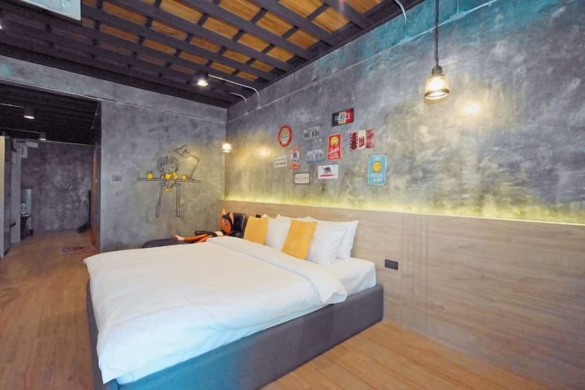 Une chambre moderne avec un grand lit, un plancher en bois et un mur orné de différents panneaux.