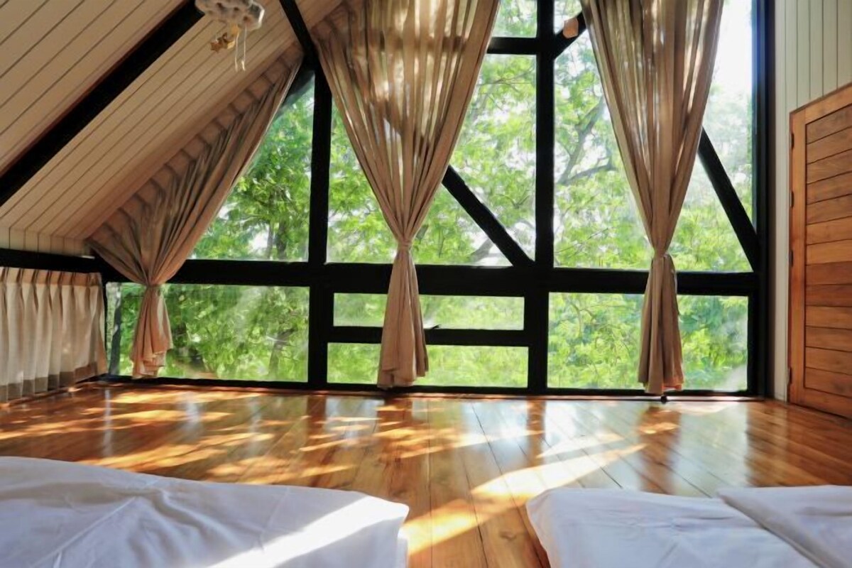 A room with a sloped ceiling, large windows, and wooden flooring.