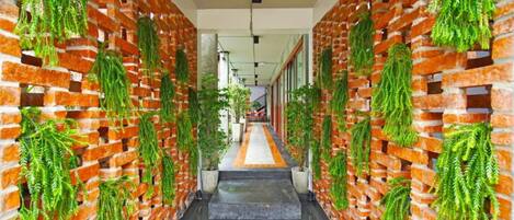 A corridor with brick walls and hanging green plants.