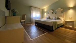 Een slaapkamer met een bed, nachtkastje, stoel en een klein bureau.