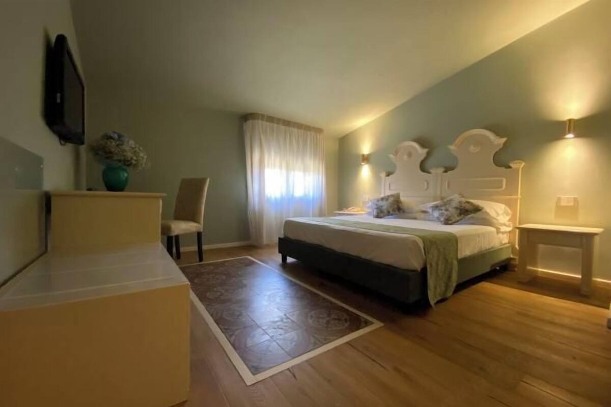 A bedroom with a bed, bedside table, chair, and a small desk.