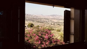 Een open deur met uitzicht op een landschap met heuvels en roze bloemen.