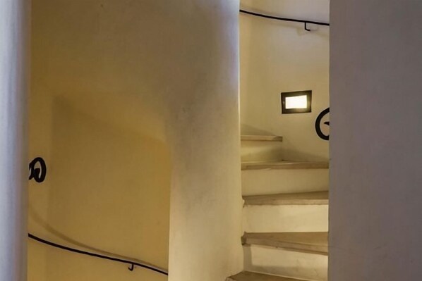 Un escalier surmonté d’un luminaire, une porte sur le côté gauche et un mur orné d’un motif circulaire.