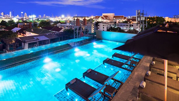 A rooftop pool with lounge chairs and a cityscape view in the background. - Chillax Heritage (Bangkok)