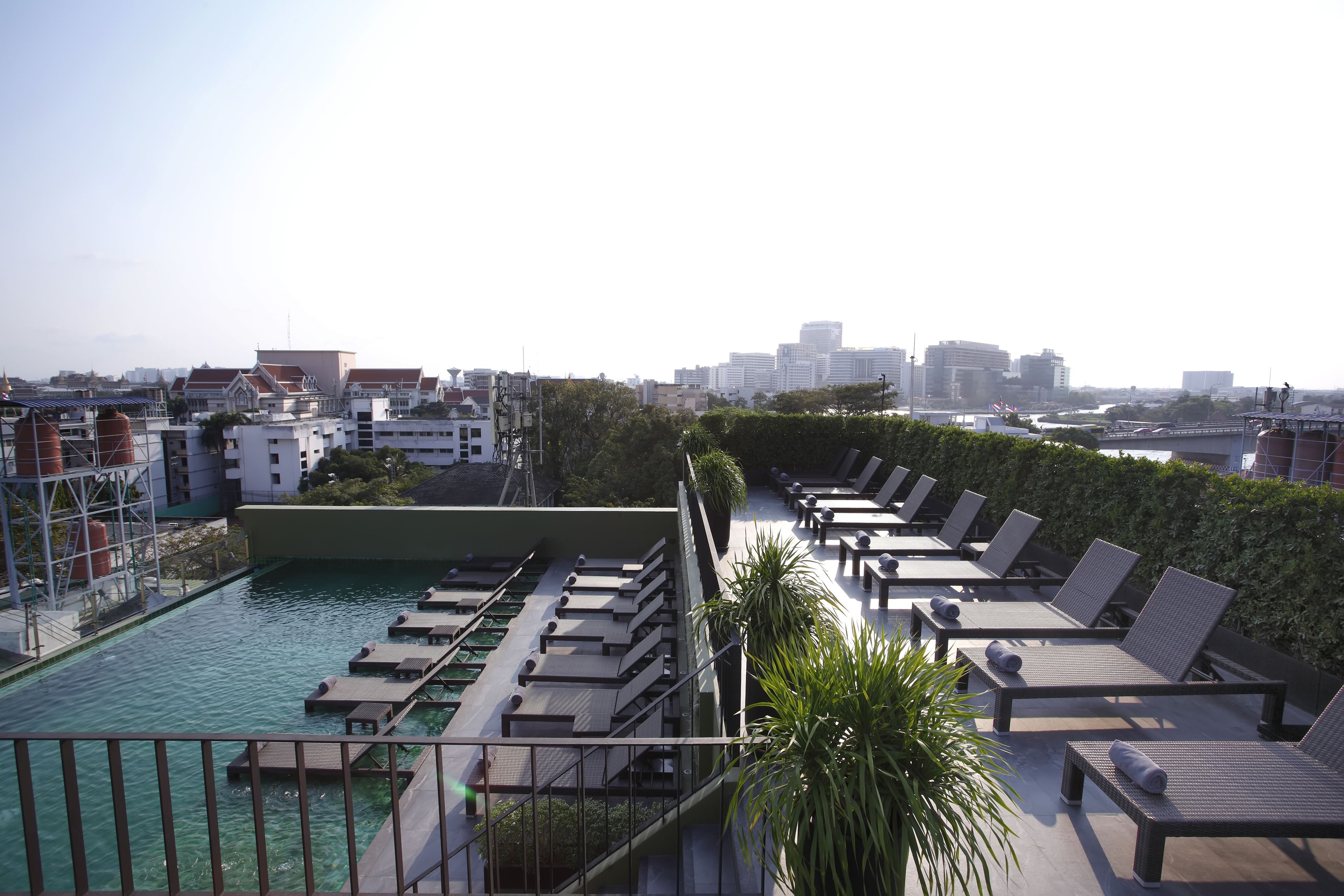Un espace piscine aménagé sur le toit, avec des chaises longues et une vue sur le paysage urbain.