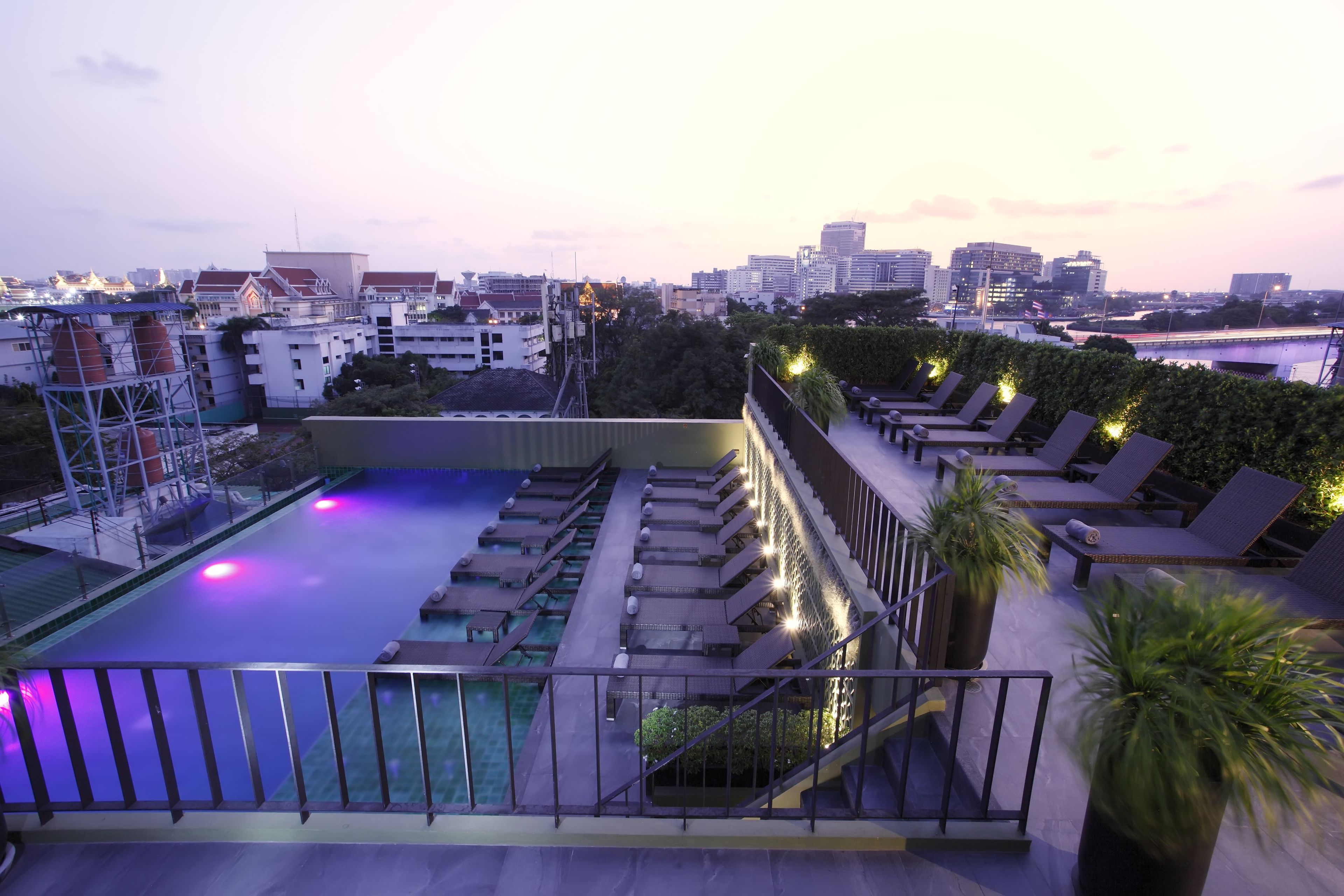 A rooftop pool area with lounge chairs and a view of the city skyline.