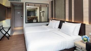 A modern hotel room with a large bed, a bedside table with a lamp, a mirror, and a view of the bathroom.