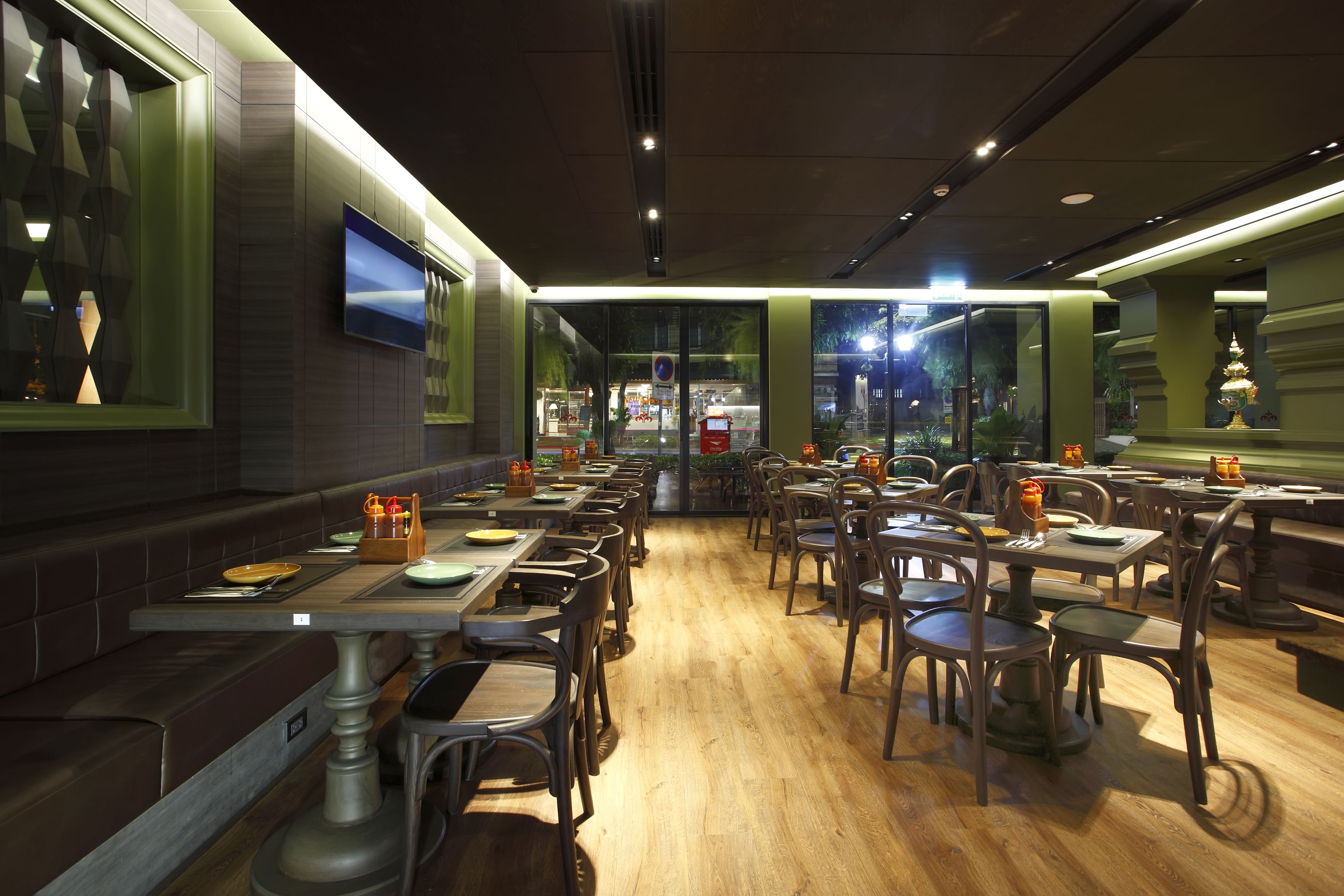 A restaurant with multiple tables and chairs, a wooden floor, and a view of the street outside.