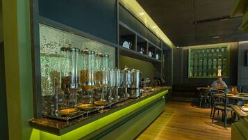 A bar area with a long counter, shelves with glassware, and a seating area with tables and chairs.