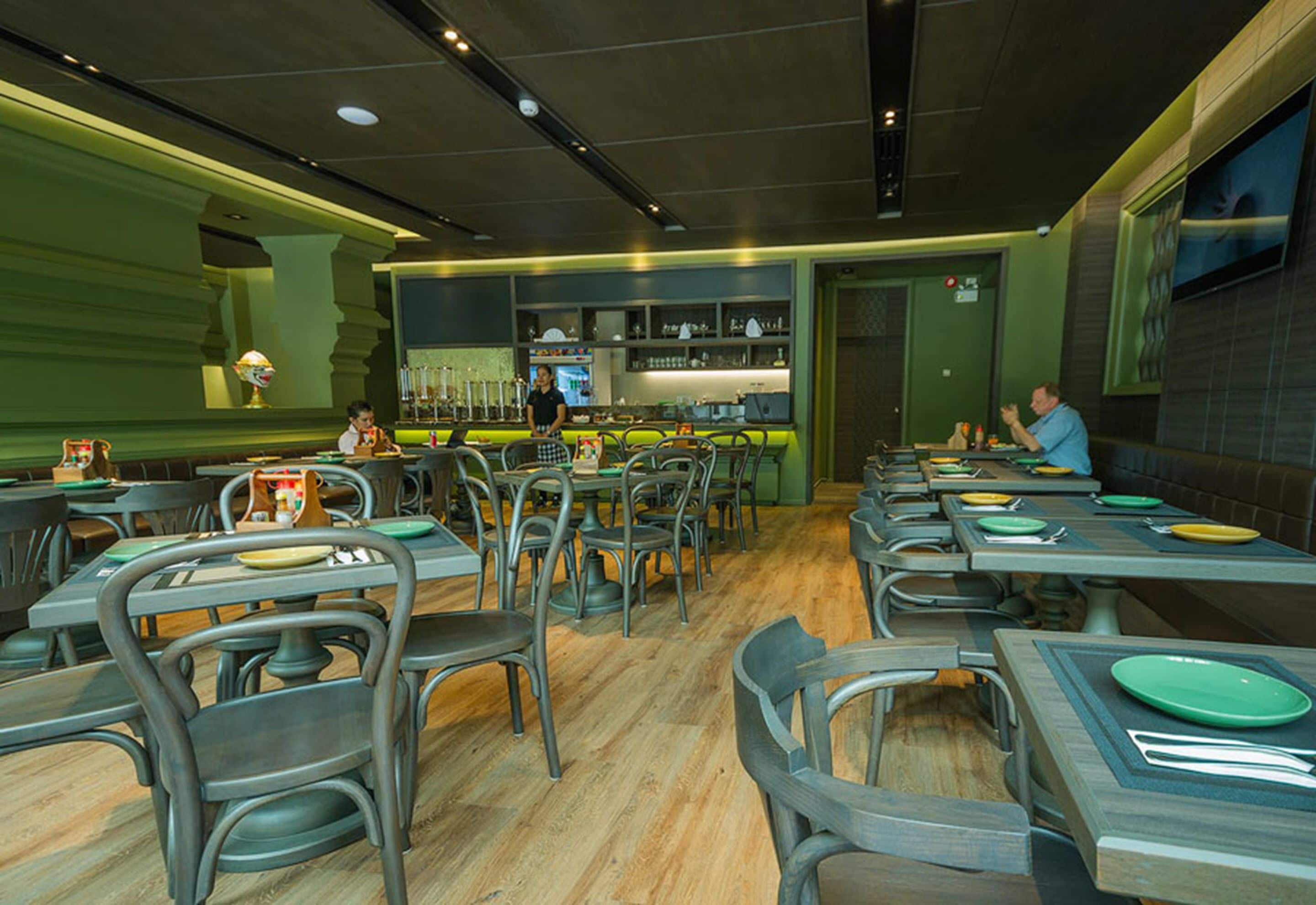 A restaurant with multiple tables and chairs, a bar area, and a counter.