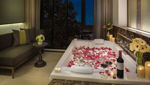 A modern bathroom with a bathtub, candles, flowers, and a bottle of wine. - Chillax Heritage (Bangkok)