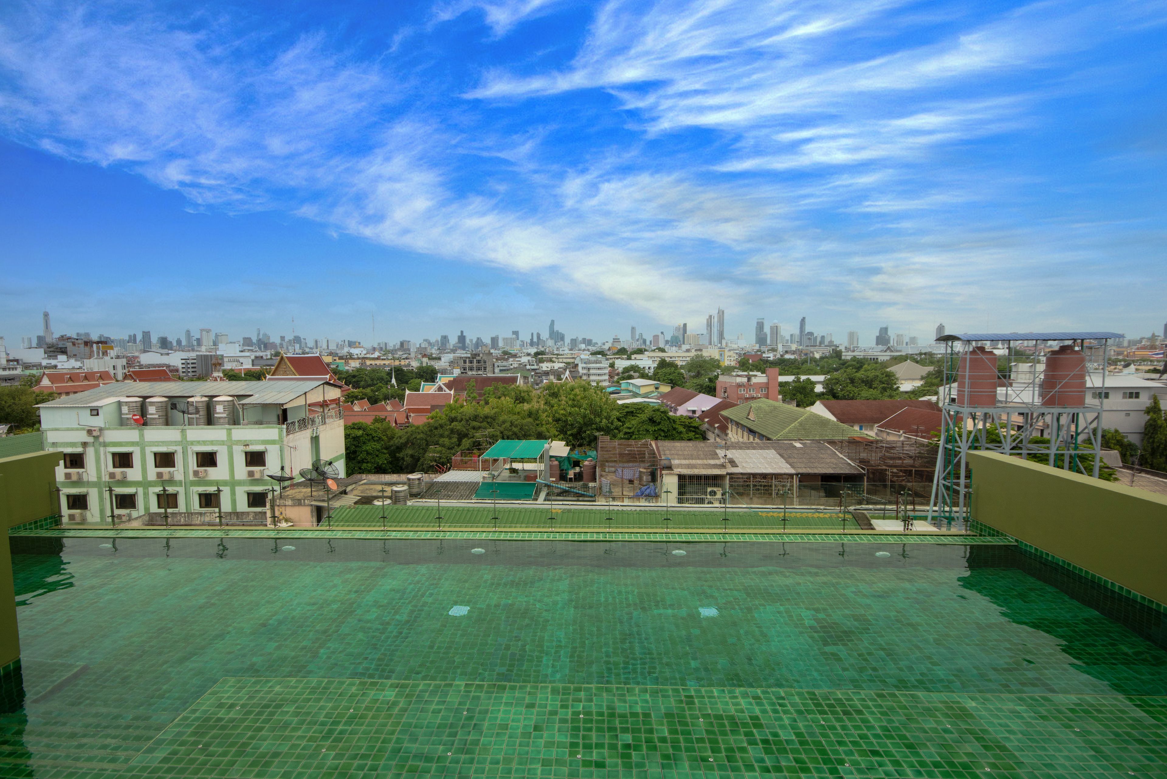 A rooftop pool with a cityscape view, surrounded by buildings and trees.