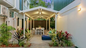 A covered patio area with a table and chairs, surrounded by potted plants. - Redhill Cairns Shared Living – Pembroke St (Parramatta Park)